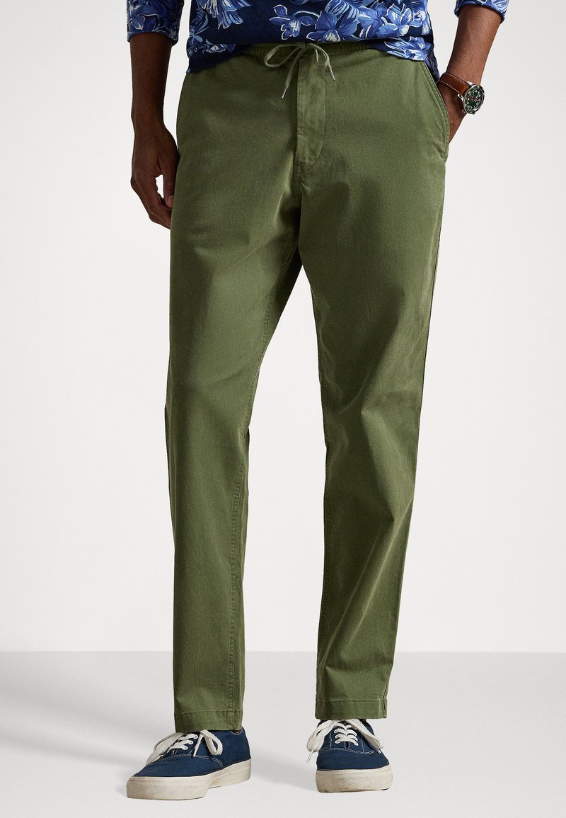 Ελαιοπράσινα, ελαφριά παντελόνια από βαμβάκι με �ελαστική μέση και κορδόνι, διαθέτουν πλάγιές τσέπες και ίσιες γραμμές, συνδυασμένα με ναυτικές αθλητικές παπούτσια.