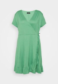 Vestido envolvente verde de mangas curtas, feito de um tecido macio. Apresenta um decote em V, detalhe franzido na lateral e uma bainha com babados.