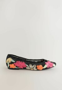 Chaussure plate noire avec des fleurs brodées vives en rose, orange, beige et vert sur les côtés.