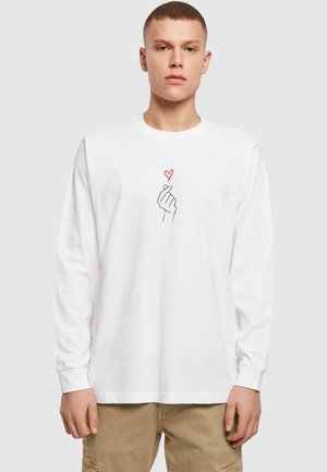 White long-sleeve T-shirt with a simple graphic of a hand forming a heart symbol in black and red. Cotton material, relaxed fit.