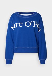 Zils apgrieztais svārki, izgatavots no kokvilnas, ar baltu tekstu "Marc O'Polo" priekšpusē, ar ribotām piedurknēm un apakšmalu.