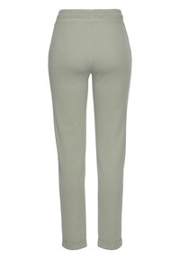 Hellgraue Sweatpants mit weicher Textur, elastischem Bund und umgeschlagenen Säumen, die ein figurbetontes Design mit schmal zulaufenden Beinen haben.