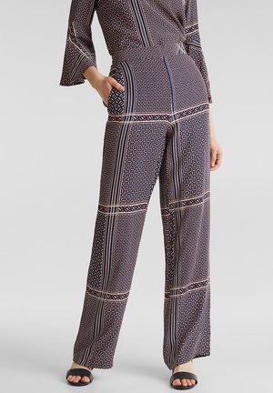 Musteroverall in Marineblau mit geometrischen Designs in Rot und Weiß. Verfügt über breite Ärmel, eine taillierte Taille und lockere, gerade Beine.