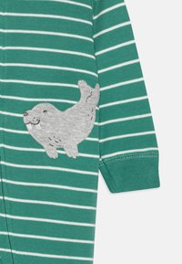 Vihreä raitaonesi, jossa on harmaa ommeltu hylkeen muotoilu mustilla yksityiskohdilla, valmistettu pehmeästä kankaasta. Resori hihansuissa mukavuuden takaamiseksi.