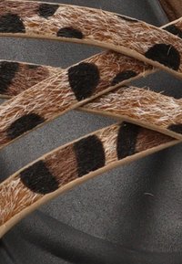 Calzado con tiras de leopardo en tonos marrón y beige fabricadas de un material suave, con una suela negra lisa. Incluye toques de manchas oscuras.