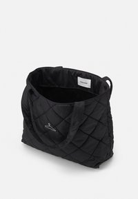 Sac fourre-tout matelassé noir avec des motifs en diamant, deux poignées et une étiquette de marque blanche à l'intérieur. Tissu doux avec un intérieur spacieux.