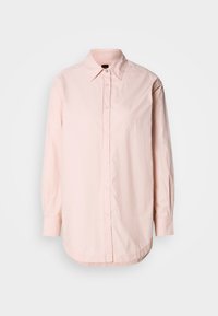 Ljusrosa långärmad skjorta med knäppning, spetsig krage och diskret broderad logotyp på bröstet, uppvisad mot en vit bakgrund.