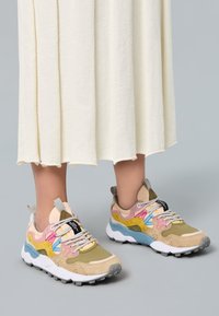Sneaker multicolori con un mix di materiali beige, rosa, verde e blu, con pannelli in suede testurizzati e mesh, e una suola bianca voluminosa.
