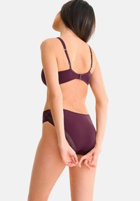 Bordeaux beha en hooggepulde slipset met verstelbare banden, voorzien van kanten accenten aan de zijkanten en een gladde textuur.