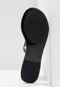 Semelle de sandale noire avec grip texturé, taille 7, sur fond blanc.
