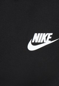 Material textil negru cu un logo alb proeminent "NIKE" și un design tip swoosh. Țesătura pare netedă, cu o textură constantă.