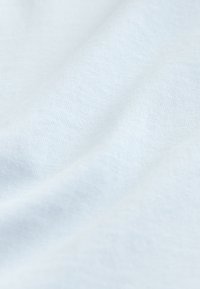 Tela azul claro suave con textura de punto fino visible y pliegues suaves que crean sombras delicadas.