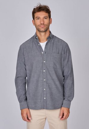 Chemise grise à manches longues, avec col et poche poitrine unique ; fabriquée dans un tissu texturé avec des boutons blancs.