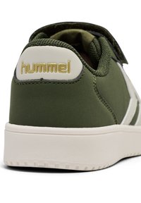 Grön tygsneaker med vadderad krage, med en vit sula och guldlogotyp på baksidan. Accentuerad med subtila sömnadsdetaljer.