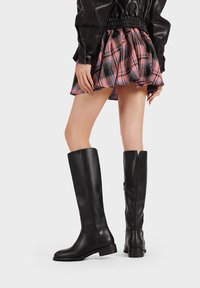 Stivali neri al ginocchio realizzati in pelle liscia, con punta rotonda e un sottile dettaglio di branding sul lato esterno. Design con tacco a blocco.