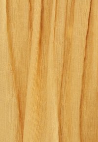 Teksturowana złoto-żółta tkanina z pionowymi paskami, lekka i lekko pomarszczona, prezentująca miękkie i naturalne wykończenie.