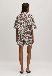 Kurzeiliges Hemd mit braun-weißer Zebra-Musterung und passenden Shorts, aus leichtem Stoff gefertigt, mit lockerem Schnitt und ohne sichtbare Verschlüsse.