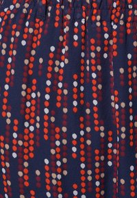 Tissu bleu marine arborant un motif de points verticaux dans des tons rouge, blanc et beige. Texture douce avec une taille élastique en haut.