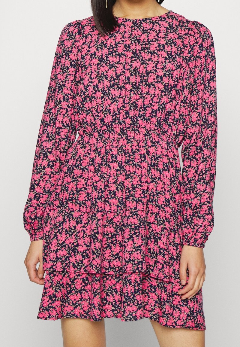 Robe mini à manches longues pour femme, à étages, avec un fond bleu marine et un motif floral rose vif, cintrée à la taille.