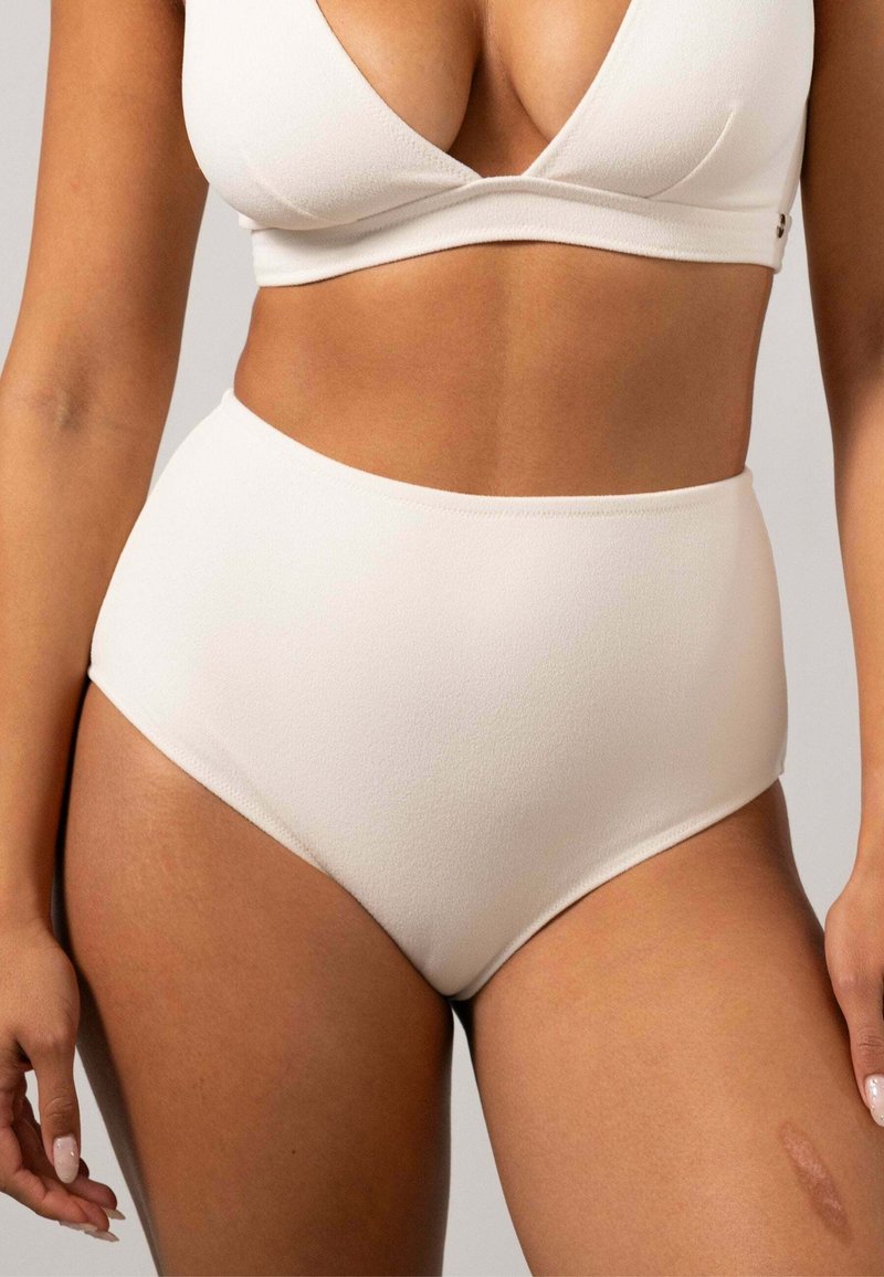 Krämfärgade högmidjade trosor i mjukt, elastiskt material. Har en slät yta med subtila sömmar och ger full täckning.