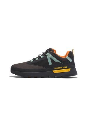 Scarpe sportive nere e marrone scuro con parte superiore in rete, dettagli verde menta, colletto arancione e logo giallo. Presentano una suola testurizzata e lacci resistenti.