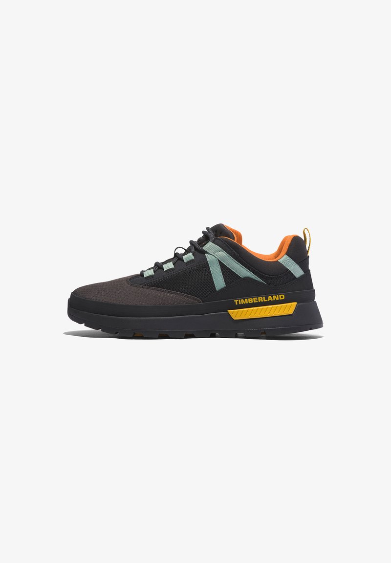 Scarpe sportive nere e marrone scuro con parte superiore in rete, dettagli verde menta, colletto arancione e logo giallo. Presentano una suola testurizzata e lacci resistenti.