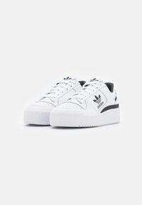 White sneakers with smooth leather upper, black accents, flat laces, and a thick white rubber sole. Adidas logo featured on the side.