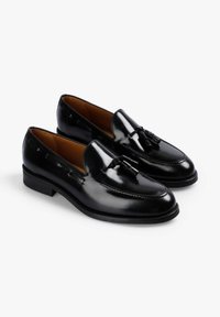 Mocasines de cuero negro con un acabado brillante, que presentan un acento decorativo de borlas, puntera redonda y un tacón bajo apilado.