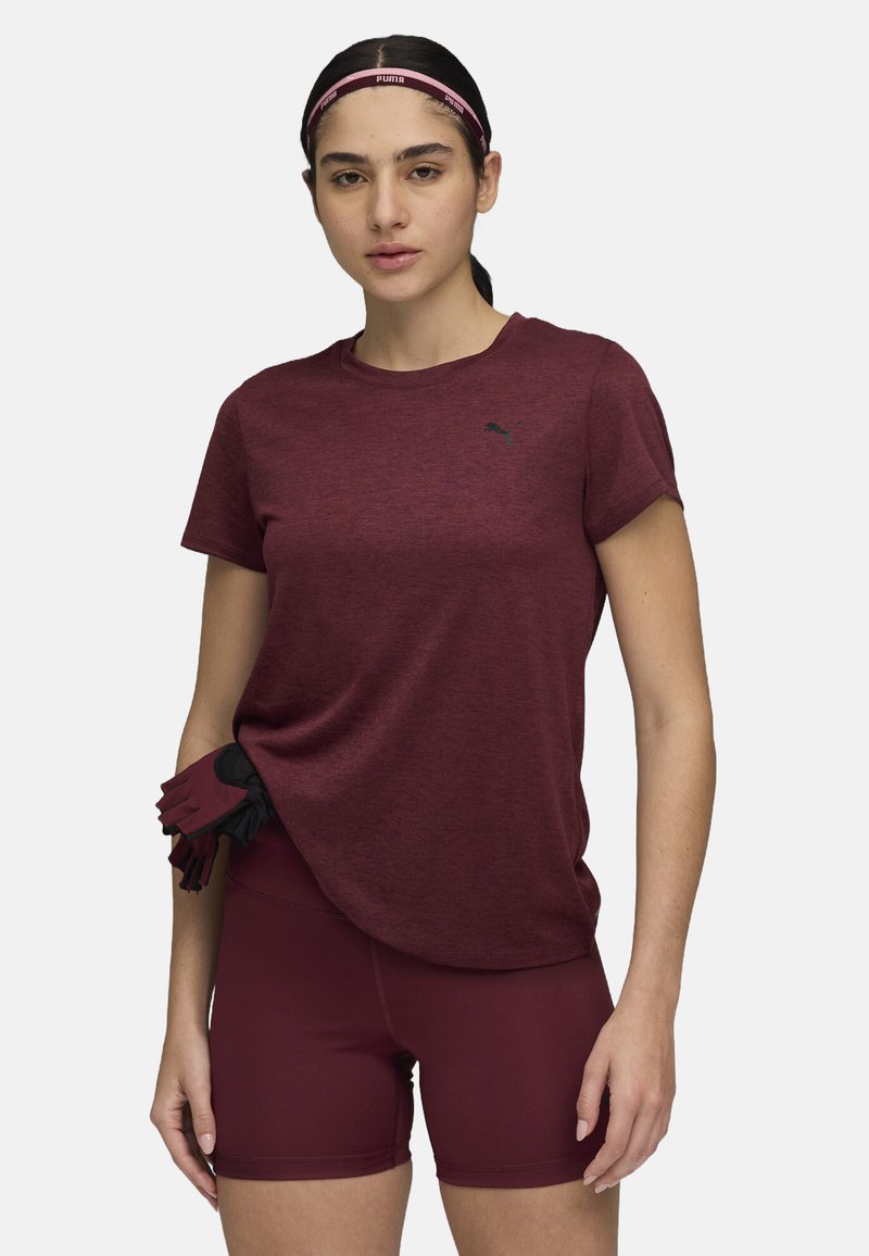 Maroon athletic t-shirt with short sleeves and a subtle logo, paired with matching maroon shorts. Fingerless gloves tucked in the waistband.
