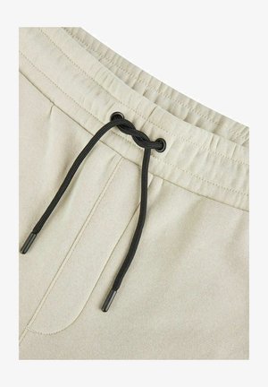 Helle beiges Shorts aus einem glatten Stoff; mit einem schwarzen Kordelzug und einer Fronttasche ausgestattet.