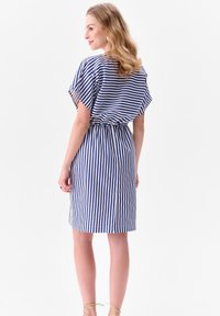 Niebieska i biała w paski krótka sukienka o luźnym kroju, elastycznym pasie i krótkich rękawach w kształcie skrzydeł. Gładka tekstura materiału z długością do kolan.