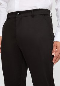Pantaloni neri con una texture liscia, design a gamba dritta, pieghe frontali sottili e chiusura con bottone in vita.