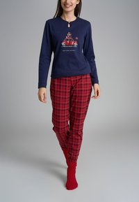 Maglietta a maniche lunghe blu navy con dettaglio a chiave e design stampato di un'auto rossa; pantaloni del pigiama a quadri rossi; calzini rossi; outfit casual da loungewear.