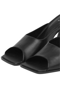 Sandales à talons ouvertes noires avec un design à bout carré, texture en cuir lisse et une large sangle sur le dessus pour le soutien.