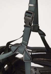 Helm mit verstellbaren, dunkelgrünen Nylonriemen und schwarzen Kunststoffschnallen. Verfügt über ein strukturiertes Design und eine robuste Innenstruktur für Sicherheit.