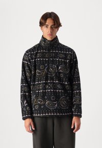 Schwarzer Fleece-Pullover mit komplexen Paisley- und geometrischen Mustern in Grün, Pink und Gelb. Verfügt über einen hohen Kragen und ein Halb-Reißverschluss-Design.