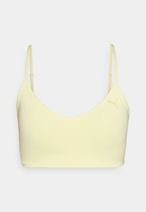 Sportovní podprsenka Puma ve světle žluté barvě, vyrobena z hladkého materiálu. Disponuje tenkými nastavitelnými ramínky a diskrétním logem na přední straně.