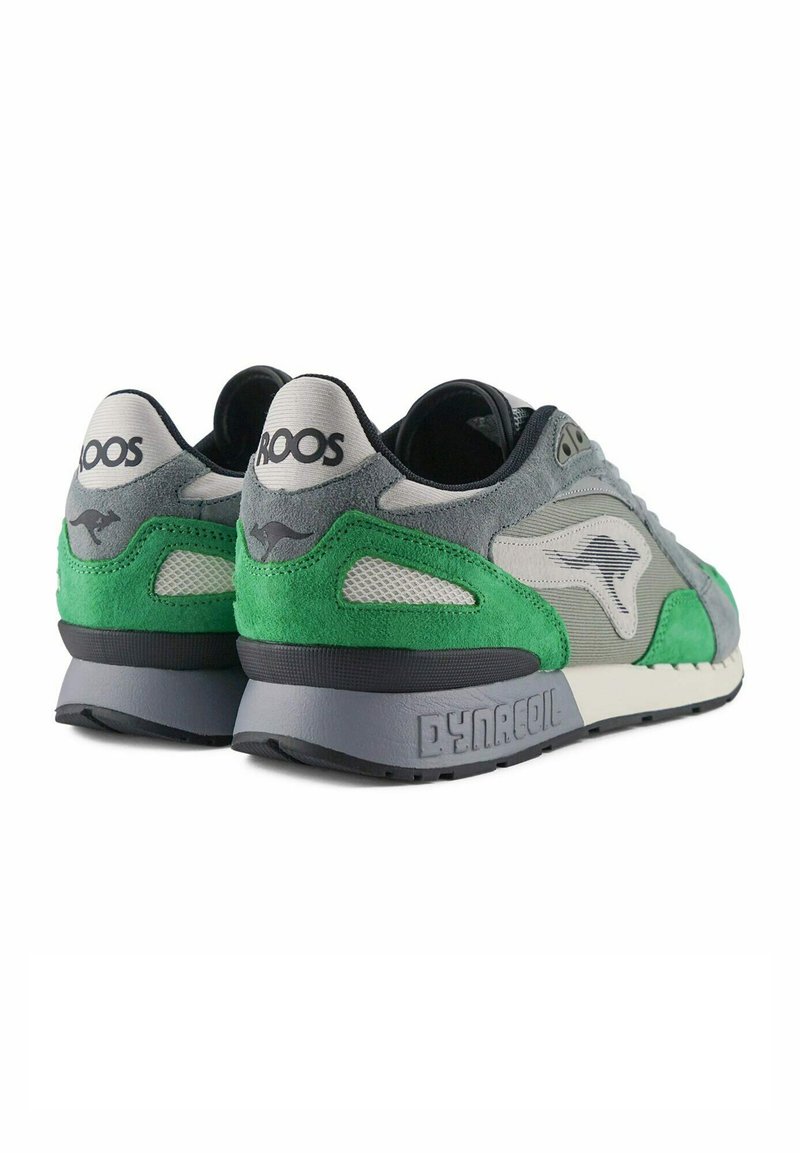 Grijze en groene suede sneakers met gaasaccenten, met een dikke grijze zool. Branding zichtbaar op de hak en zijkant. Retro hardloopschoen ontwerp.