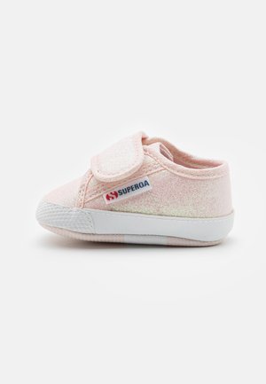 Chaussure en toile rose clair avec une finition brillante, bride Velcro et semelle en caoutchouc blanche ; comporte le logo Superga sur le côté.