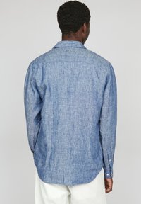 Camicia azzurro chiaro a maniche lunghe realizzata in tessuto testurizzato con un motivo sottile. Presenta un colletto classico e dettagli con bottoni sui polsini.