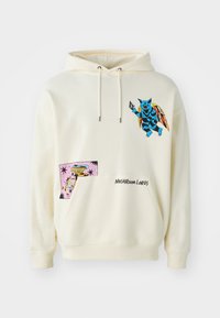 Cremefarvet hættebluse med et blåt væsen grafisk og en farverig lap med et fantasifuldt design. Broderet tekst lyder "MUSHROOM LORDS."