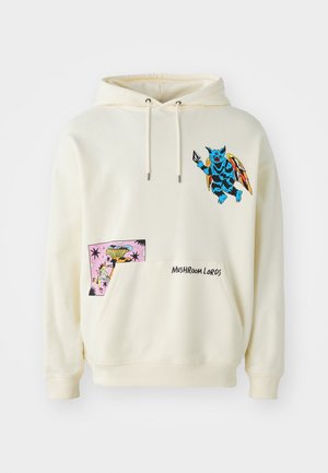 Sudadera color crema con un gráfico de una criatura azul y un parche colorido con un diseño caprichoso. El texto bordado dice "LORDES HONGOS".