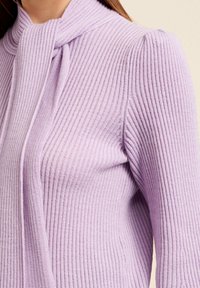 Levandulový pruhovaný pletený svetr s zavazovacím detailem u krku. Má nafouklá ramena a přiléhavý střih na těle.