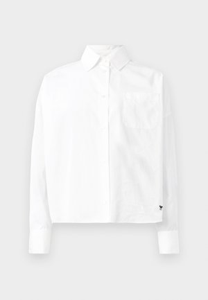 Camisa branca de manga longa com colarinho pontudo, um bolso no peito e mangas com punho. Feita de um tecido liso e leve.