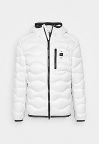 Vit pufferjacka med huva, med kviltade mönster, en framzipper och svarta detaljer på zipperns och ärmsluten. Liten bröstficka finns.