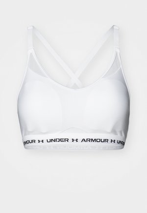 White sports bra with cross-back straps, made from smooth material. Features a black branded waistband with "UNDER ARMOUR" text.