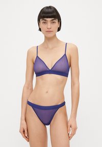 Paarse doorschijnende bralette met verstelbare bandjes, met een driehoekig ontwerp, en een bijpassende doorschijnende string met een stevige tailleband.