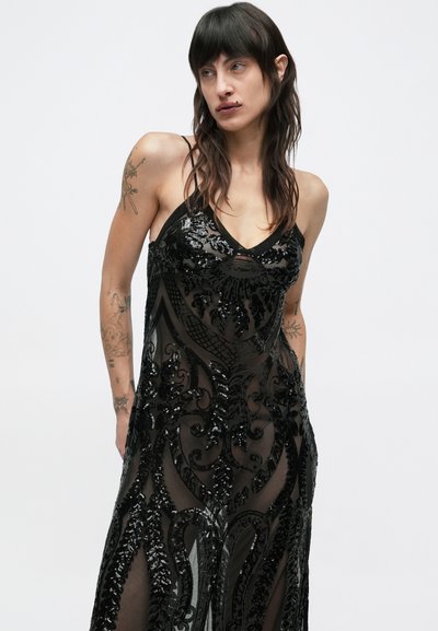 Mustast läbipaistvast materjalist kleit, mis on kaunistatud keerukate tikanditega ja V-kujulise kaelusega. Õhukesed rihmad viivad vooluva ja rikkaliku kujunduseni, millel on lõikega sümpaatne keha.