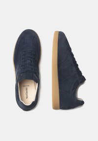 Zapatillas de ante azul marino con suela de goma, que presentan una puntera redondeada y cordones planos. Los paneles laterales tienen sutiles acentos texturizados.