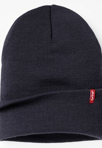 Donkergrijze gebreide beanie met een omgeslagen boord. Heeft een klein rood Levi's label aan de zijkant. Zachte textuur en een aansluitend ontwerp.